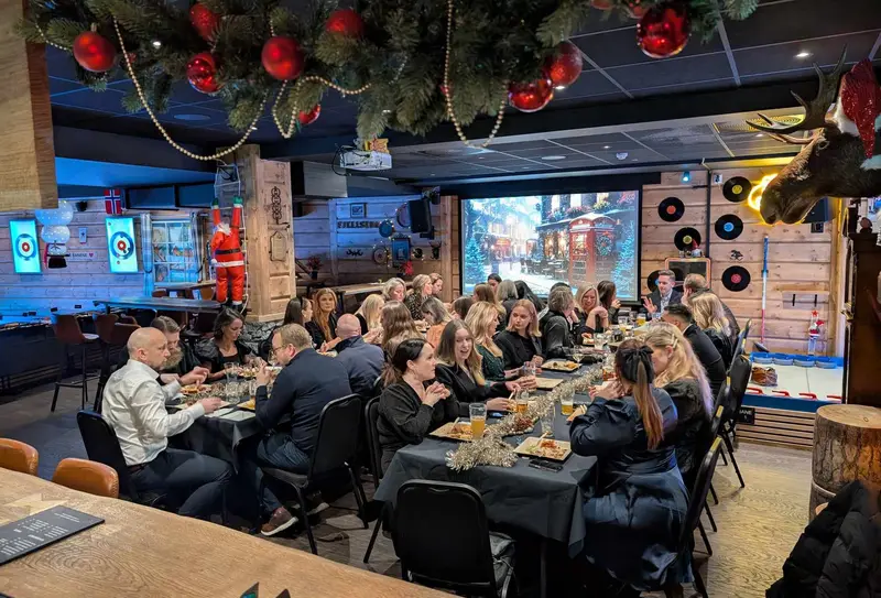Christmas party at a long table in Fjellstua, decorated for Christmas